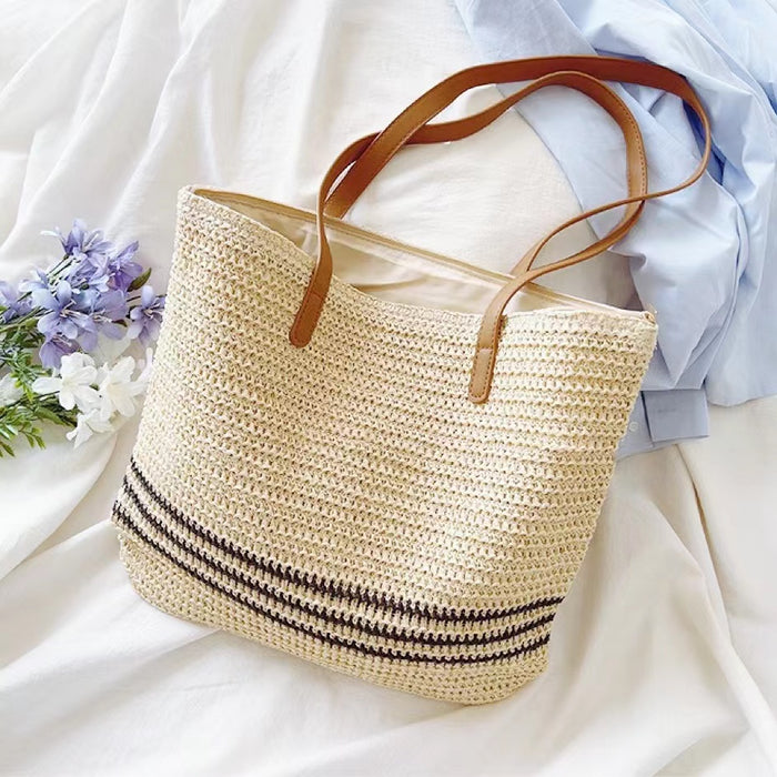 Front view of Beige woven straw tote bag with brown PU leather straps and three black stripes.