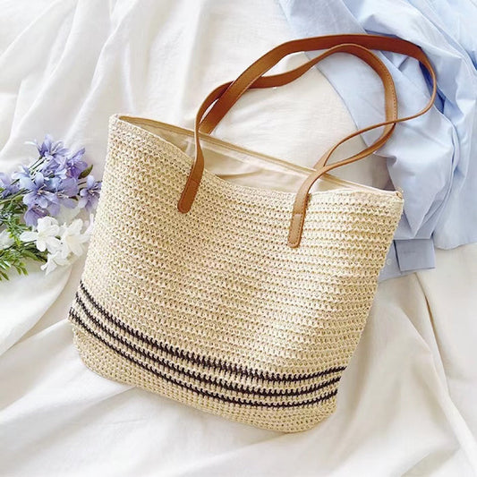 Front view of Beige woven straw tote bag with brown PU leather straps and three black stripes.