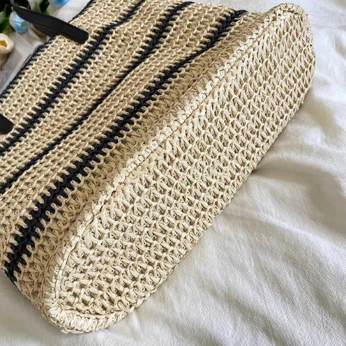 Close-up of Woven straw tote bag with black stripes, showcasing the bottom.