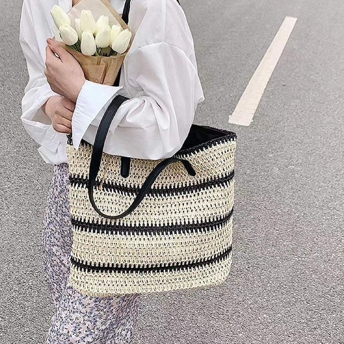 Model carring a Woven Straw Tote Bag with Black Stripe, great for everyday carry and travel.