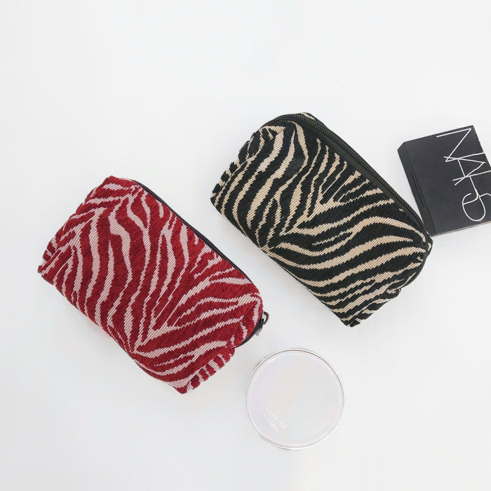 Front view of Two zebra print makeup bags, one red and one black.