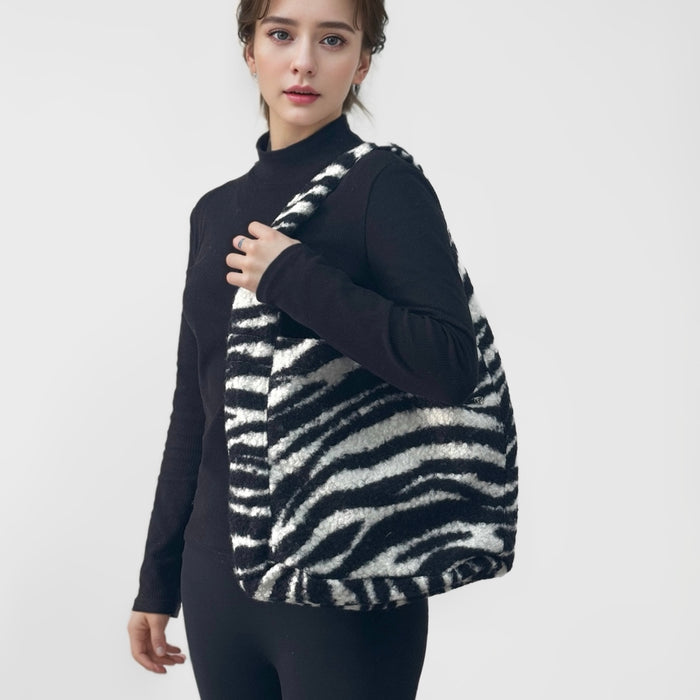 Woman carrying a fluffy black and white zebra print tweed tote bag with a magnetic clasp.