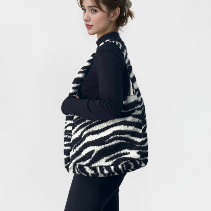 Woman carrying a fluffy black and white zebra print polyester tote bag with a magnetic clasp.