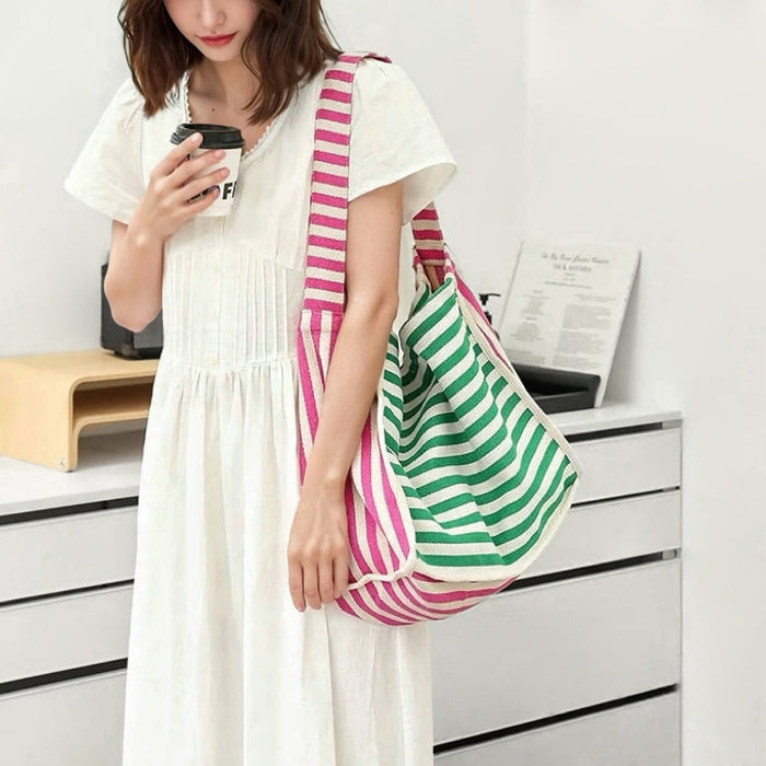 Model carrying a striped tote bag as crossbody,  easy for commuting and weekends.